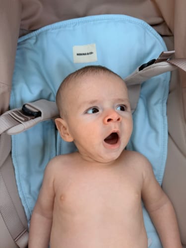 Customer's dusty blue Colchoneta Universal in a stroller with a baby sitting comfortably inside