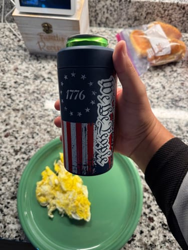 Customer's Universal Buddy can cooler with USA flag design being held in a hand over a green plate.