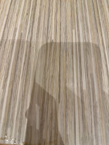 Reviewer's view of a wooden surface, showing only a shadow and the texture of the grain.