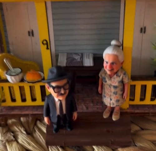 Customer's custom chibi couples figurine displayed on a miniature porch setting.
