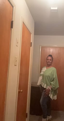 Customer's green and white polka-dot batwing sleeve top worn with jeans, standing indoors.
