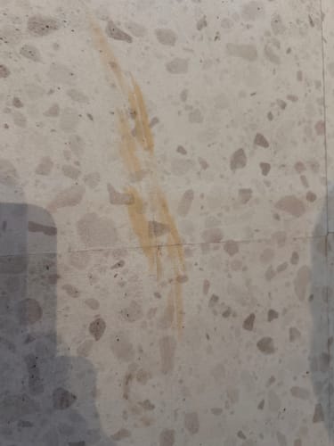 Customer's Lisboa Terrazzo fliser med synlige gulaktige misfarginger på den lyse overflaten.