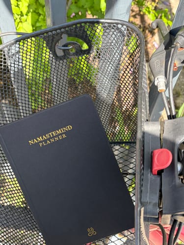Customer's black Namastemind Planner in a bicycle basket outdoors