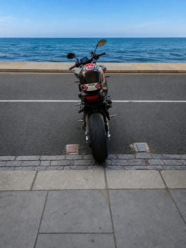 Customer's motorcycle parked by the sea after Bracket Fitment Service, showing the new plate and indicators.