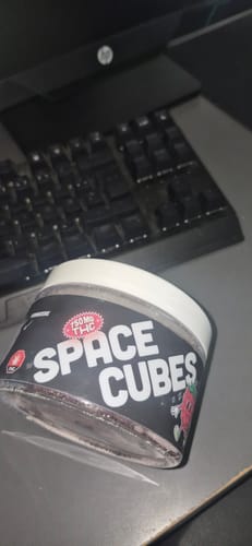 Kundenfoto der THC Space Cubes Dose auf einem Computerschreibtisch mit Tastatur.