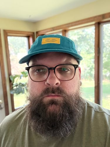 Customer wearing a teal Big Camp Hat with a yellow label, indoors.