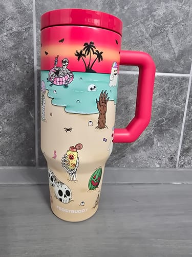 Reviewer's Thicc Buddy mug in pink and beige featuring a beach-themed graphic, standing on a tiled surface.