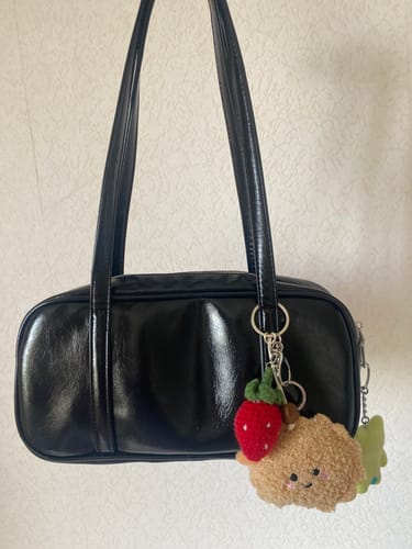 Customer's black Nana Inspired Bag with a hanging strawberry and fuzzy cookie charm.