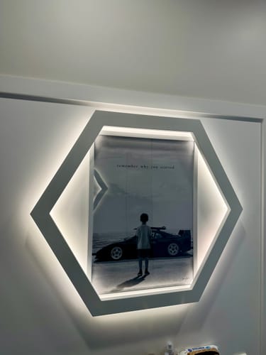 Customer's REMEMBER art print mounted in a white, hexagonal illuminated frame on a wall.