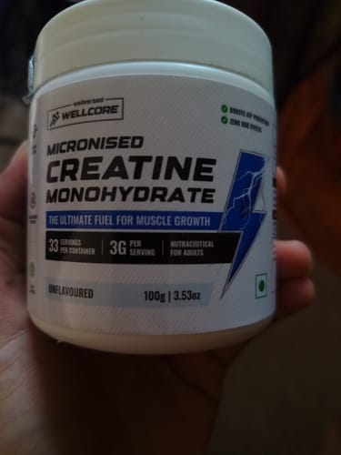 Customer's hand holding a white tub of Wellcore Micronised Creatine Monohydrate.