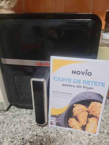 Customer's black Novio StonePro air fryer sitting next to its recipe book on a kitchen counter.