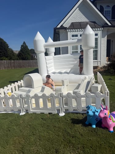 Customer's Essential Playground set including a large white bounce house and foam play shapes in a backyard.