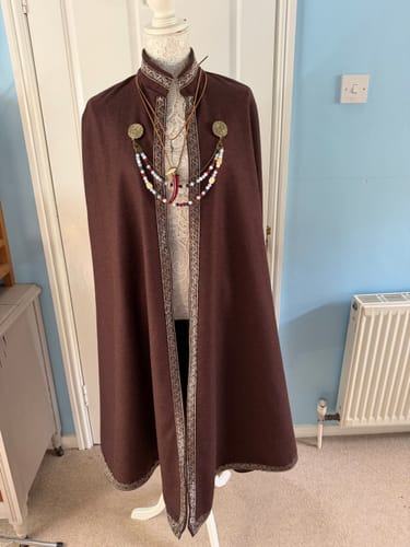 Customer's brown wool blend fabric made into a Viking-style cape with decorative trim on a mannequin.