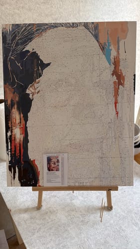 Customer's Custom Paint by Numbers Kit canvas on an easel, showing an unfinished portrait with color-coded sections.