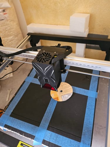 Customer's 3D printer head assembly in operation on a build plate with blue tape.