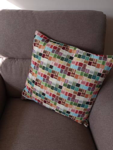 Customer's colourful squares tapestry fabric cushion on a brown armchair