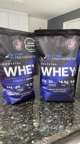 Reviewer's two bags of Proteína Whey Sin Sabor, one vanilla flavored and one unflavored, resting on a dark surface.