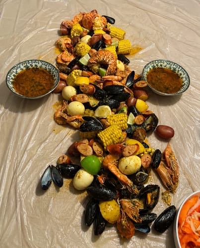Reviewer's Cajun Seafood Boil Bomb result, featuring mussels, shrimp, corn, and potatoes spread on a table.