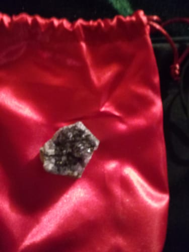 Customer's VIP Crystal Club amethyst cluster resting on a bright red satin drawstring bag