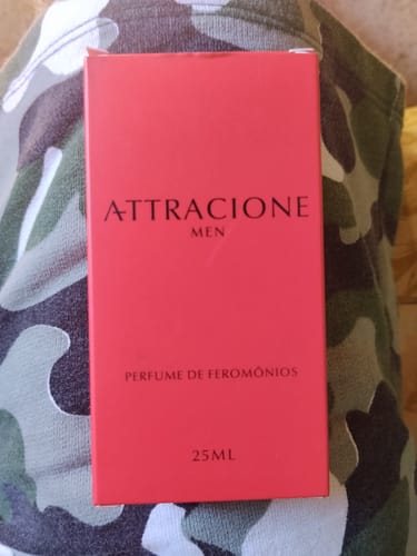 Customer's Attracione Men perfume box in red, held against a camouflaged fabric background.