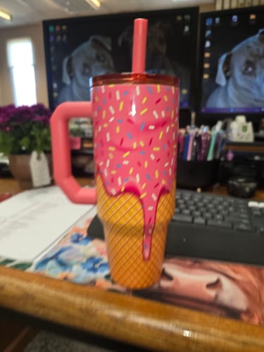 Customer's pink ice cream Thicc Buddy 40oz mug with straw standing on a desk with a keyboard.