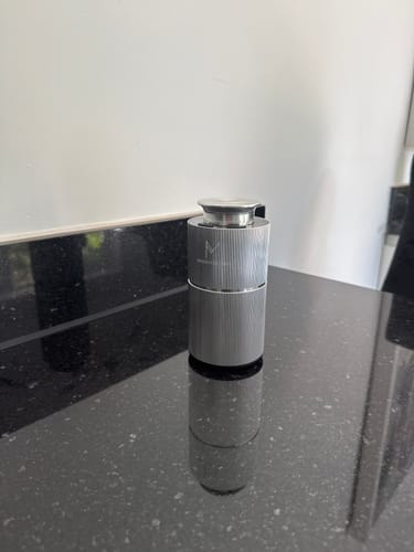 Customer's MistMini portable diffuser in metallic grey, standing on a sleek black countertop.