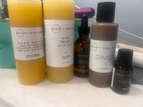 Customer's Body Serum collection displayed with other skincare products on a bathroom counter.