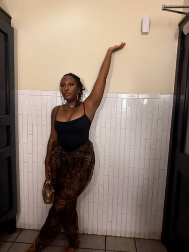 Reviewer wearing Chiffon Print Shirred Pants paired with a black bodysuit in front of a white tiled wall