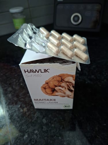 Kundenfoto einer Hawlik Maitake Extrakt und Pulver Packung mit einem Blisterstreifen beige-farbener Kapseln darauf.