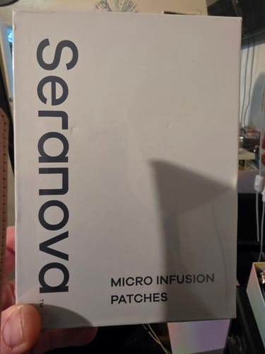 Customer's hand holding the white Seranova Micro Infusion Patches box packaging
