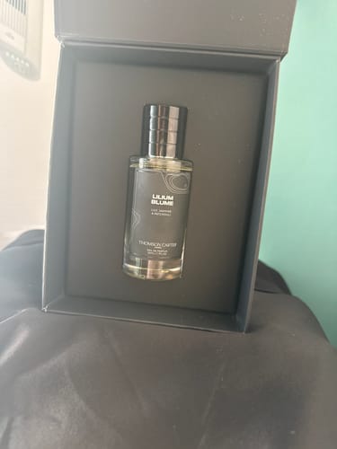 Customer's Lilium Blume perfume bottle centered inside an elegant, dark branded gift box.