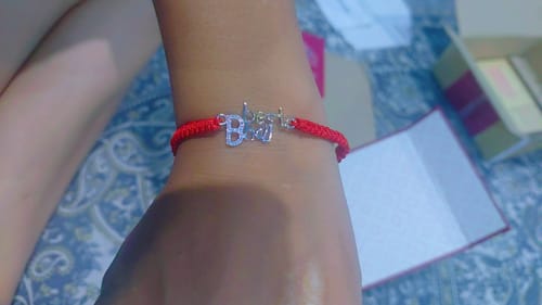Customer's hand wearing the Best Bhai Rakhi, featuring a silver motif on a red thread.