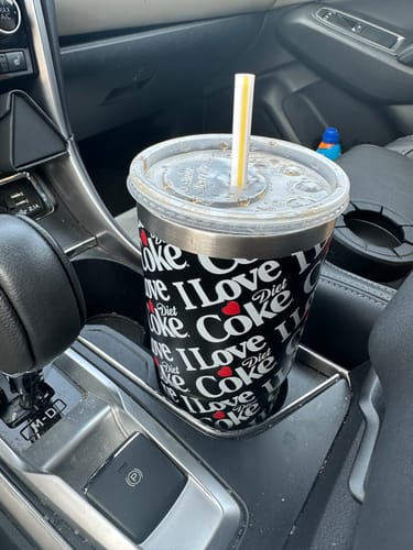 Customer's black Diet Coke To-Go Buddy cup holder insulator with a drink inside a car.
