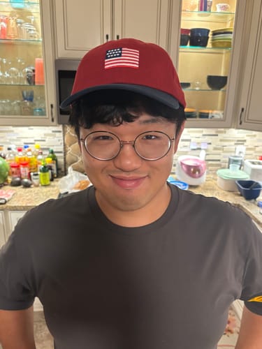 Customer's Big Dad Hat USA in red with a dark brim being worn by a person in a kitchen.