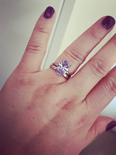 Customer's Aura Birthstone Ring, featuring a large, sparkling oval stone on a metal band worn on a finger.