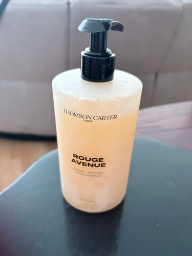 Customer's peach-colored bottle of Rouge Avenue body wash with a black pump, sitting on a dark surface.