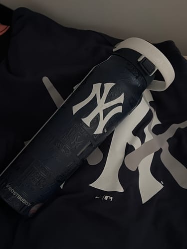 Customer's navy Bottle Buddy 32oz featuring a New York Yankees logo, resting on a matching logo shirt.