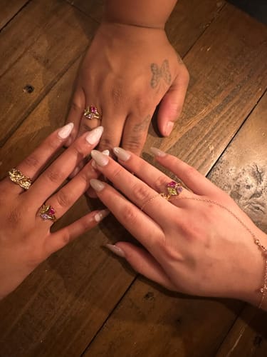 Reviewer's hands displaying three Vienne Birthstone Rings on fingers against a wooden surface