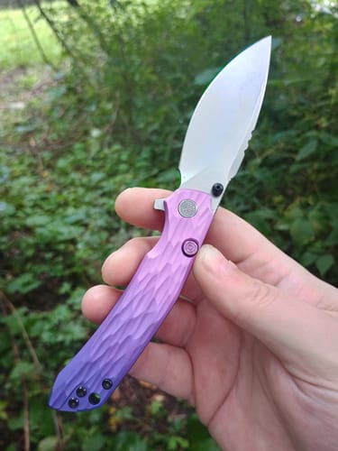 Customer's Miguron Knives Celora held in hand, showing a textured purple aluminum handle and a bright stonewash blade.