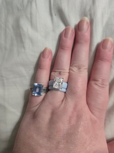 Customer's light blue Emerald Cut CZ Silicone Ring Set worn on a finger next to a separate blue gemstone ring.