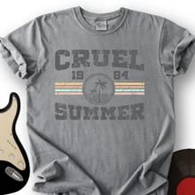 Customer's gray Cruel Summer 1984 T-shirt with retro-style graphic, next to a guitar and vinyl record.