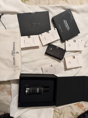 Customer's Smoke & Mirrors fragrance bottle in open black box, with discovery kit samples and branded pouch.