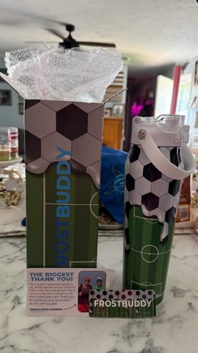 Customer's Bottle Buddy in soccer print packaging, shown with the matching water bottle on a white counter.