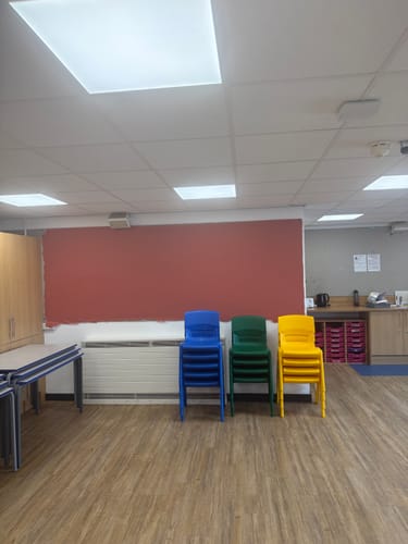 Reviewer's plain textured polyester fabric applied as a flat, red wall covering in a classroom setting.