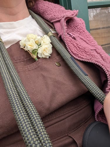 Customer's brown Brumby Suit with flowers tucked into the front pocket, worn with a pink fleece jacket.