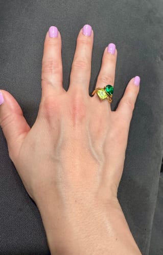 Customer's Navae Birthstone Ring with a light green rectangular stone and a dark green pear stone on a gold band.