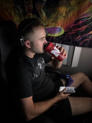 Customer's Universal Buddy can cooler in red with an N logo, held by a person drinking from it while gaming.