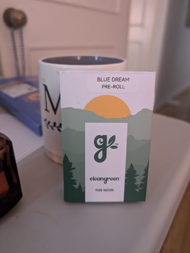 Customer's Blue Dream Pre-Roll packaging sitting on a table next to a white mug.