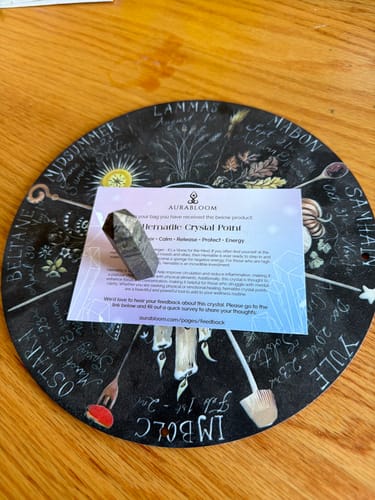 Reviewer's Hematite Crystal Point from the VIP Crystal Club program, resting on a decorative, circular wheel mat.