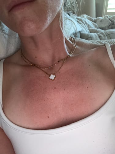 Reviewer wearing the gold Sasha Multi-Colored Necklace with a white clover pendant.